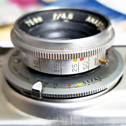 lower lens labeled 'COATED VAREX', '8' on aperture scale is red, yellow triangle between 5.6 and 8; yellow dot above '25', red dot above '50' on focus scale